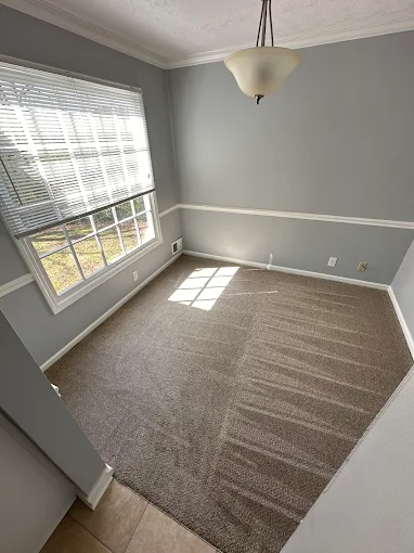 Empty room with gray walls, carpet, window with blinds, and hanging light